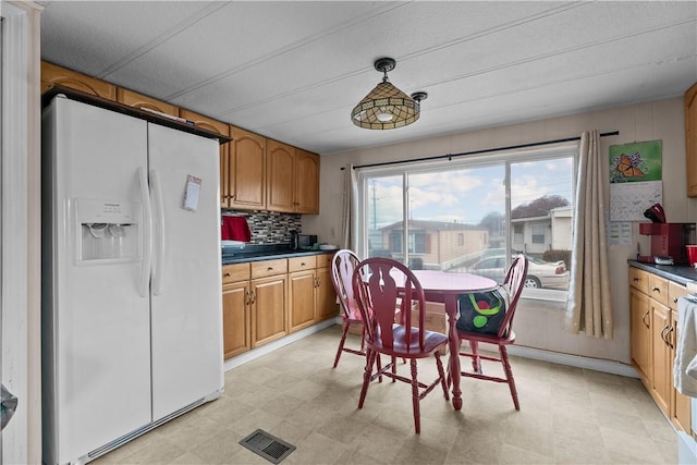 kitchen with tasteful backsplash, white refrigerator with ice dispenser, visible vents, and light floors