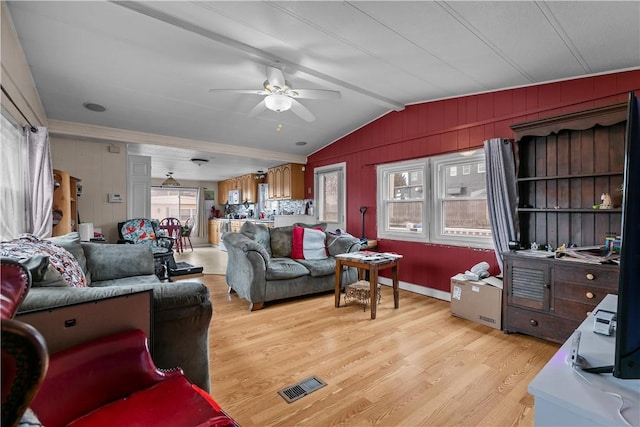 living room featuring visible vents, light wood finished floors, lofted ceiling with beams, and a wealth of natural light