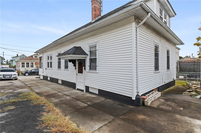 view of side of property with a chimney and fence