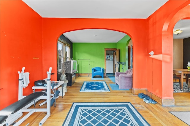 exercise area with arched walkways and wood finished floors