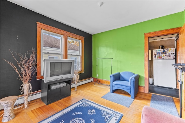 sitting room featuring a baseboard radiator, baseboards, and wood finished floors