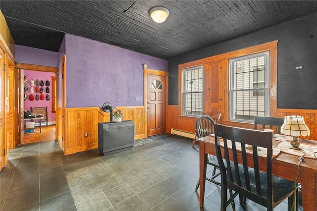 dining space featuring wainscoting, a wood stove, and wooden walls