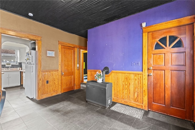 interior space with a wainscoted wall, arched walkways, and wooden walls