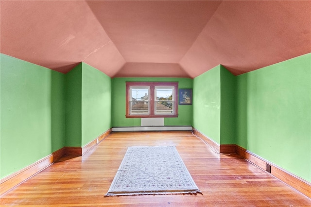 additional living space featuring lofted ceiling, a baseboard radiator, baseboards, and wood finished floors