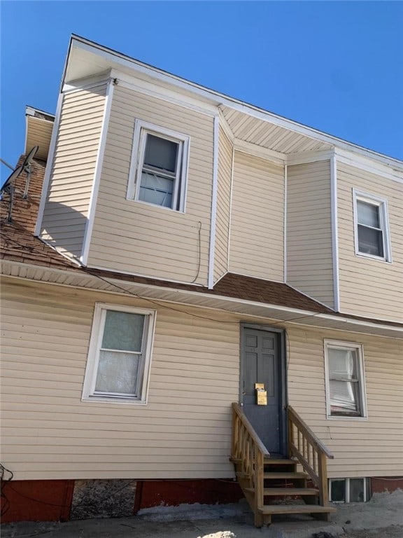 rear view of property featuring a shingled roof and entry steps