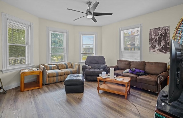 living room featuring a ceiling fan, baseboards, and wood finished floors