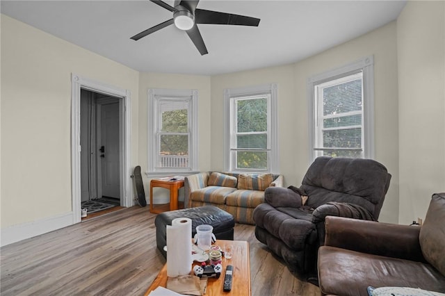 living area featuring ceiling fan, baseboards, and wood finished floors