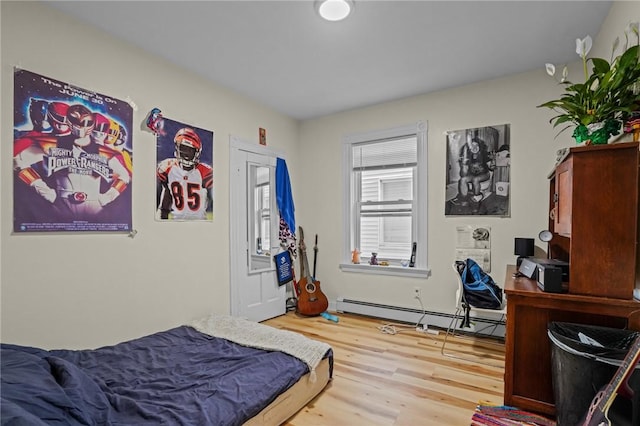 bedroom featuring a baseboard heating unit and wood finished floors