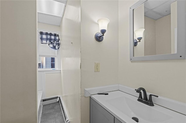 bathroom with a baseboard heating unit, a drop ceiling, and vanity