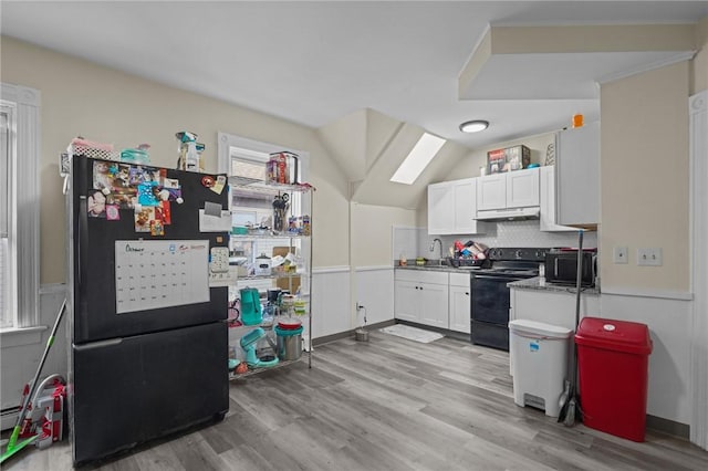 kitchen featuring light wood-style flooring, under cabinet range hood, black appliances, white cabinetry, and a sink