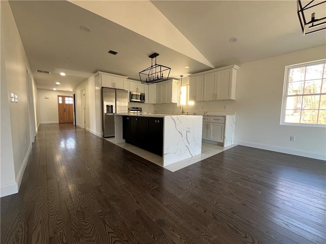 kitchen with lofted ceiling, light countertops, appliances with stainless steel finishes, a kitchen island, and wood finished floors