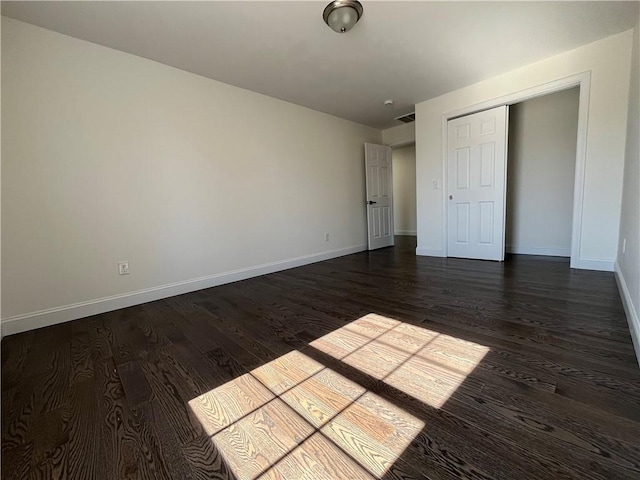 unfurnished bedroom with dark wood-style floors, visible vents, and baseboards