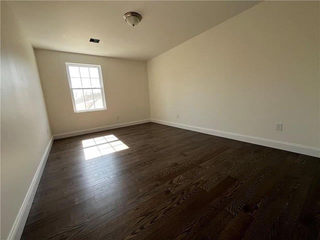 unfurnished room featuring baseboards and dark wood finished floors