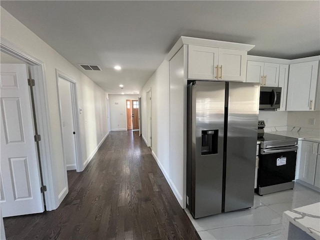 kitchen featuring white cabinetry, visible vents, stainless steel appliances, and light stone counters