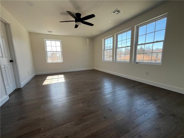 spare room with dark wood-style flooring, visible vents, ceiling fan, and baseboards