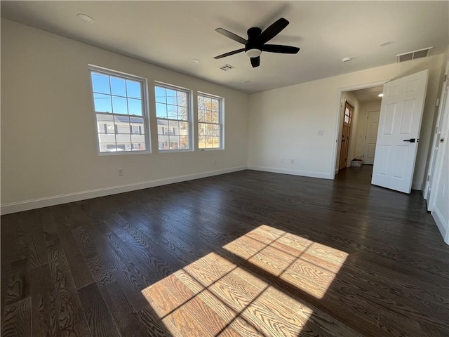 spare room with dark wood-style floors, visible vents, ceiling fan, and baseboards