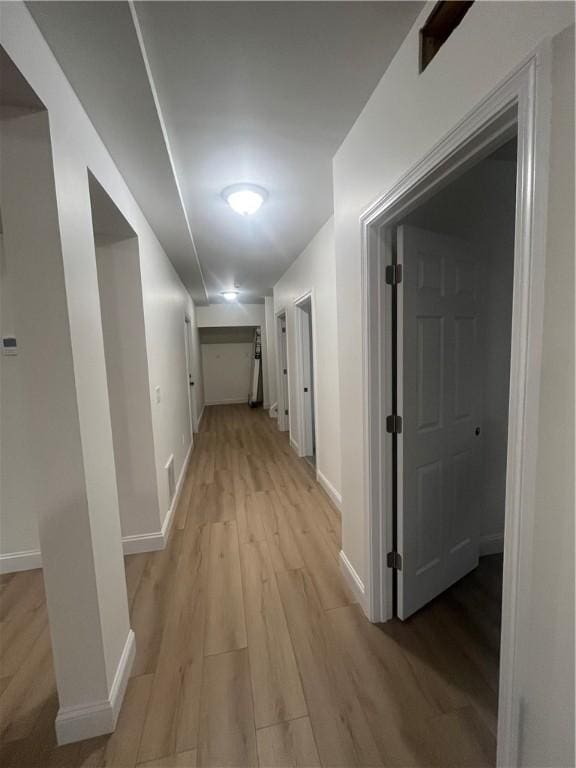 hall featuring light wood-style flooring and baseboards