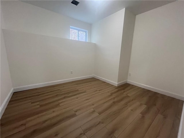 spare room featuring baseboards and wood finished floors