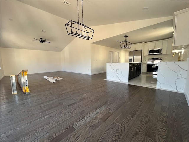 kitchen with appliances with stainless steel finishes, open floor plan, a center island, vaulted ceiling, and pendant lighting