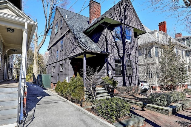 view of side of home with a shingled roof and a chimney