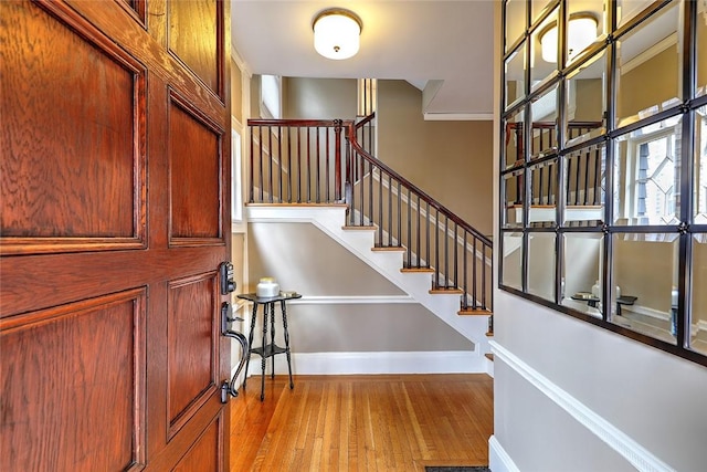 foyer entrance featuring stairway, baseboards, and wood finished floors