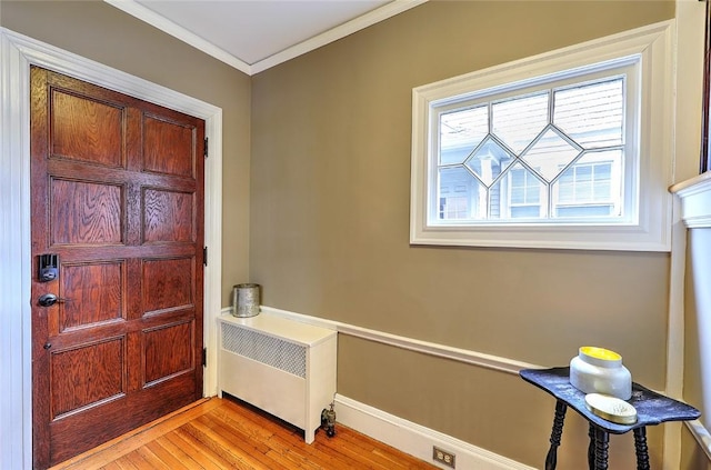 entryway with ornamental molding, light wood-type flooring, radiator, and baseboards