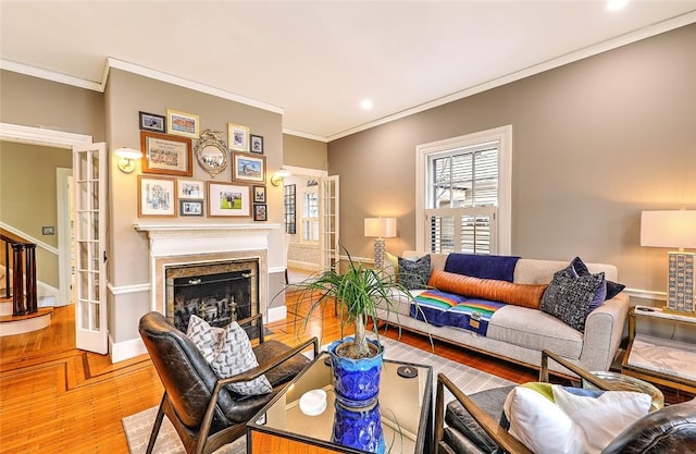 living area with ornamental molding, stairway, a fireplace, and wood finished floors