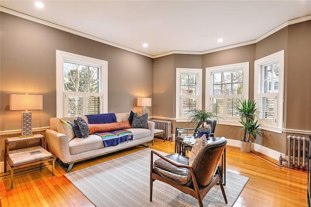 living room featuring light wood finished floors, radiator heating unit, plenty of natural light, and crown molding