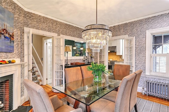 dining space featuring radiator, crown molding, a chandelier, and wood finished floors