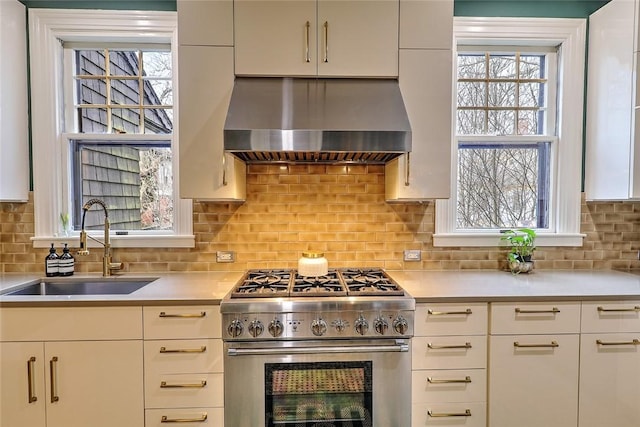 kitchen with a sink, high end stainless steel range oven, extractor fan, light countertops, and backsplash