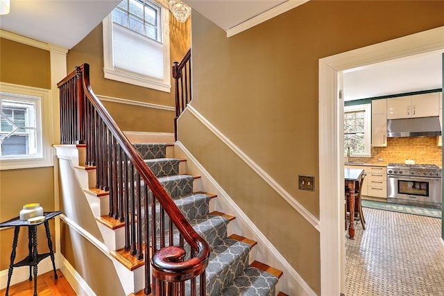 stairway with ornamental molding, a healthy amount of sunlight, and baseboards