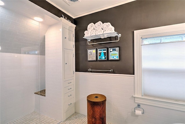 bathroom featuring visible vents, tiled shower, wainscoting, and tile walls