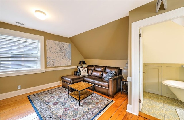 living room with lofted ceiling, visible vents, baseboards, and hardwood / wood-style floors