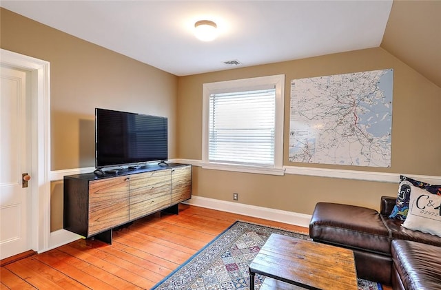 living area featuring vaulted ceiling, baseboards, visible vents, and light wood-style floors