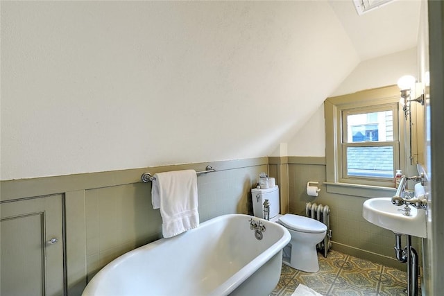 bathroom with toilet, a soaking tub, radiator heating unit, and lofted ceiling