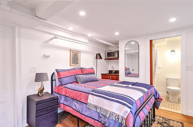 bedroom featuring light wood-type flooring, ensuite bath, and recessed lighting