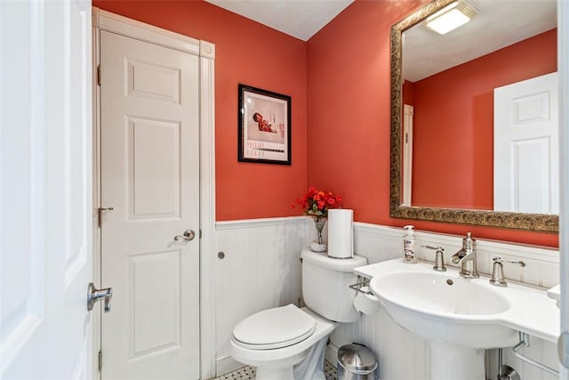 bathroom featuring a wainscoted wall, a sink, and toilet