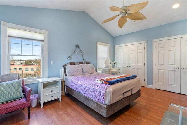 bedroom featuring ceiling fan, vaulted ceiling, multiple closets, and wood finished floors