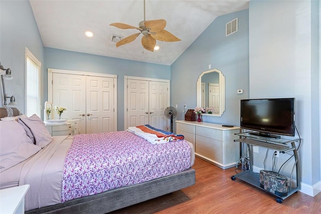 bedroom featuring lofted ceiling, visible vents, multiple closets, and wood finished floors