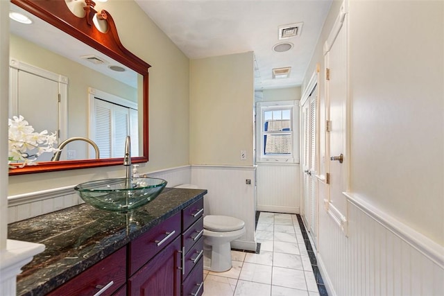 full bathroom featuring toilet, vanity, visible vents, and wainscoting