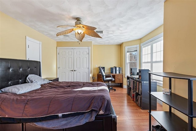 bedroom with visible vents, a ceiling fan, light wood-style flooring, a textured ceiling, and a closet