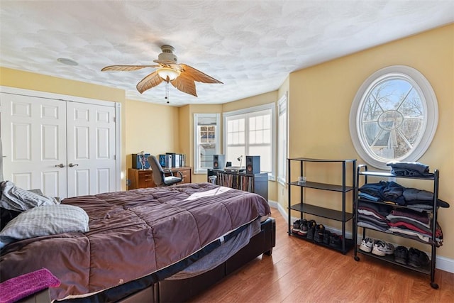 bedroom featuring baseboards, a ceiling fan, wood finished floors, a textured ceiling, and a closet