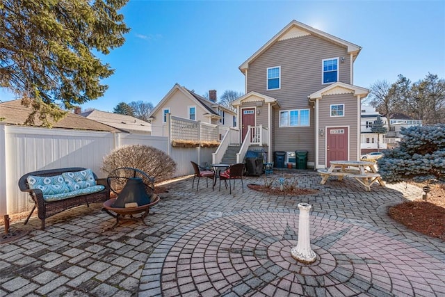 rear view of property featuring a patio, a fire pit, and fence