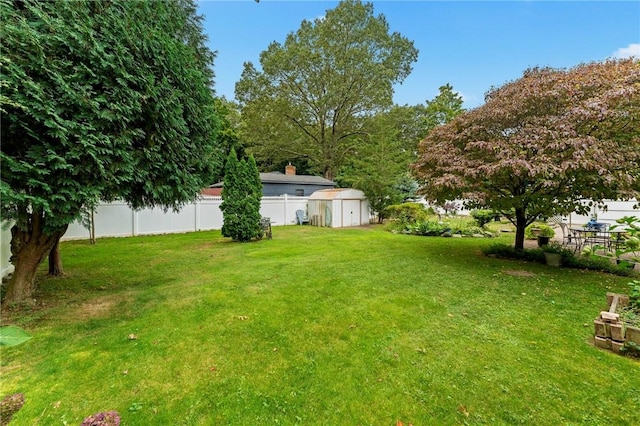 view of yard with fence, a storage unit, and an outbuilding