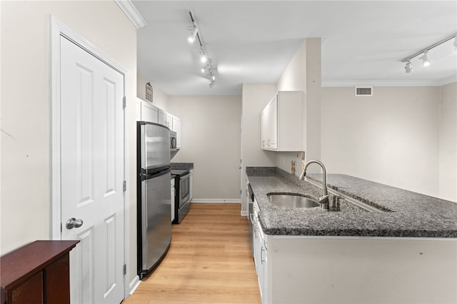 kitchen featuring visible vents, white cabinets, a peninsula, stainless steel appliances, and a sink