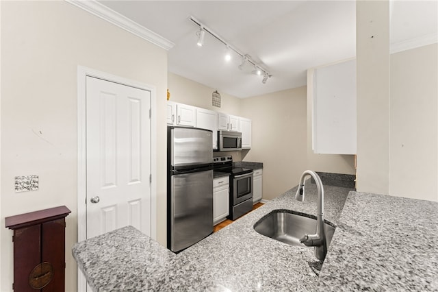 kitchen with a peninsula, a sink, white cabinets, appliances with stainless steel finishes, and crown molding