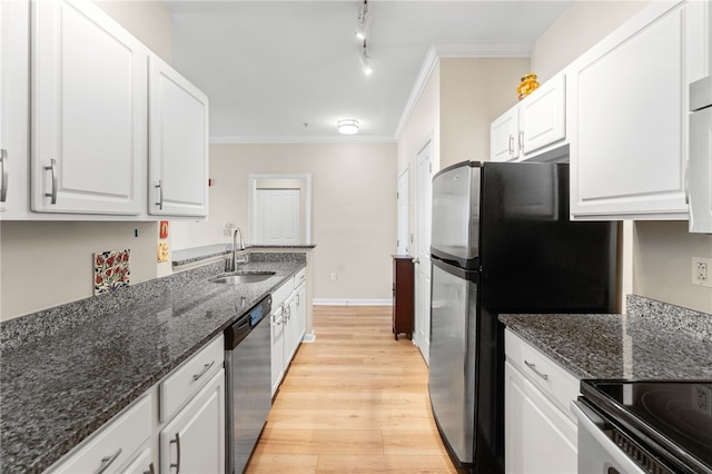 kitchen featuring appliances with stainless steel finishes, white cabinets, a sink, and light wood-style flooring