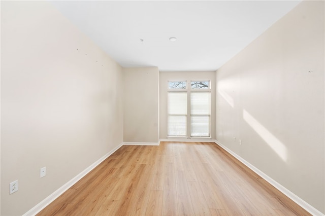 empty room featuring light wood finished floors and baseboards