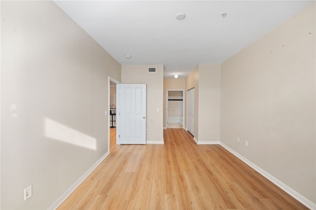 spare room featuring light wood finished floors, baseboards, and visible vents