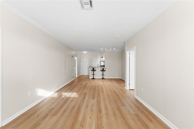 interior space featuring visible vents, baseboards, light wood-type flooring, rail lighting, and crown molding